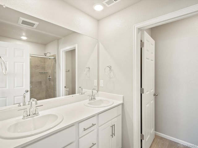 bathroom with tiled shower, hardwood / wood-style flooring, vanity, and toilet