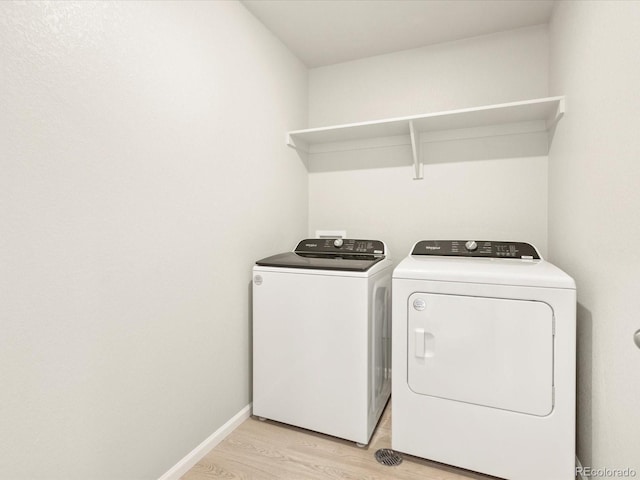 laundry area with independent washer and dryer and light hardwood / wood-style flooring