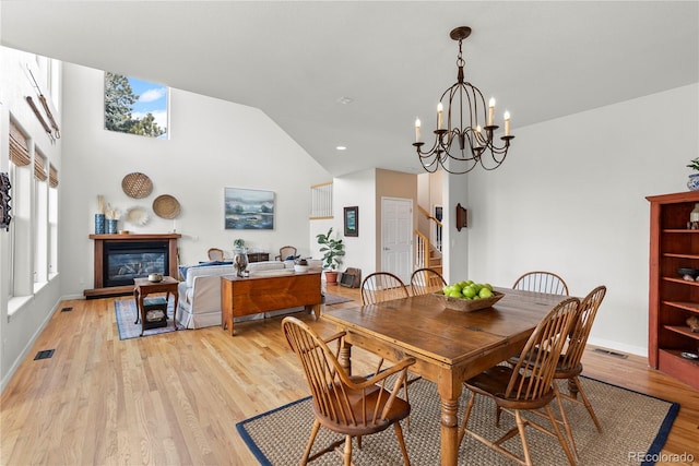 dining space with a glass covered fireplace, a healthy amount of sunlight, visible vents, and light wood finished floors