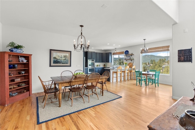 dining space featuring baseboards, light wood-style floors, recessed lighting, and a notable chandelier