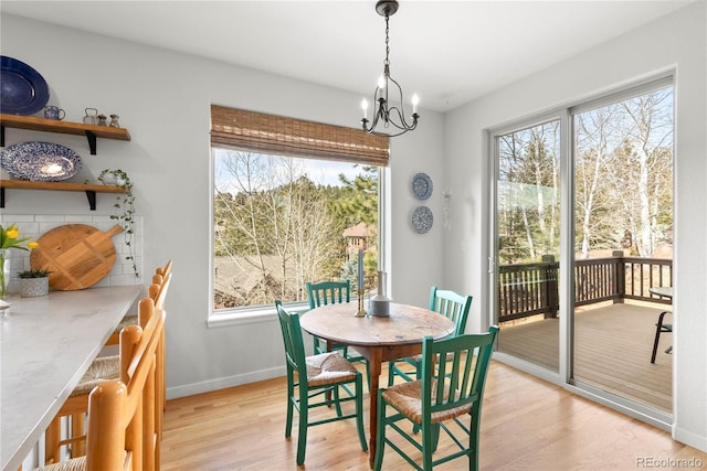 dining room with light wood-style floors, a wealth of natural light, a chandelier, and baseboards