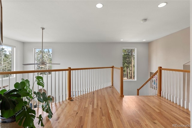 hall featuring wood finished floors, an upstairs landing, and recessed lighting