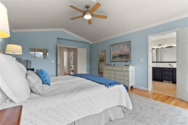 bedroom featuring lofted ceiling, ornamental molding, ensuite bathroom, light wood-style floors, and a sink