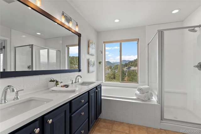 bathroom with double vanity, a garden tub, a shower stall, and a sink