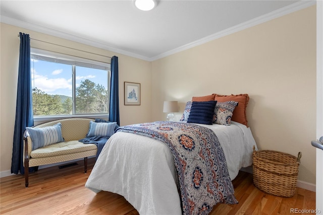 bedroom with baseboards, ornamental molding, and wood finished floors