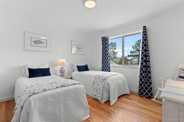 bedroom featuring ornamental molding, light wood-style flooring, and baseboards