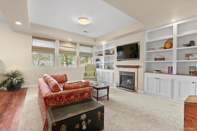 living room featuring visible vents, baseboards, built in shelves, a fireplace, and recessed lighting