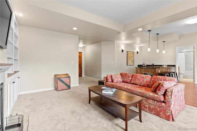 living room featuring light carpet, a fireplace, baseboards, and recessed lighting