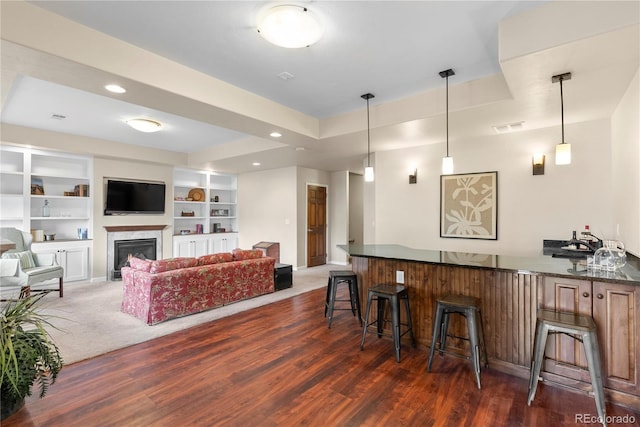 bar with recessed lighting, a fireplace, wood finished floors, visible vents, and a tray ceiling