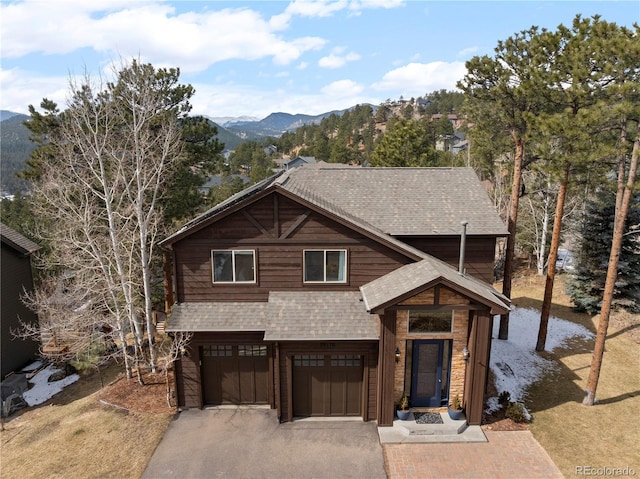 chalet / cabin with roof with shingles, driveway, an attached garage, and a mountain view