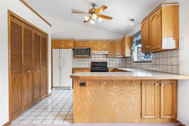 kitchen with a peninsula, freestanding refrigerator, black electric range, under cabinet range hood, and vaulted ceiling