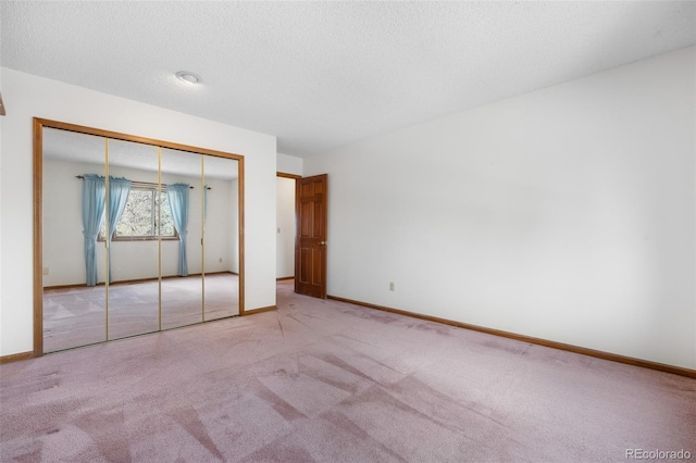 unfurnished bedroom featuring a textured ceiling, carpet floors, a closet, and baseboards