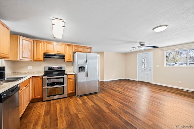 kitchen featuring appliances with stainless steel finishes, dark wood finished floors, a ceiling fan, under cabinet range hood, and visible vents