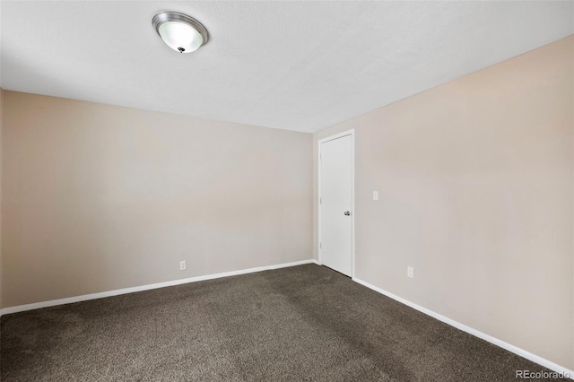 spare room featuring baseboards and dark colored carpet