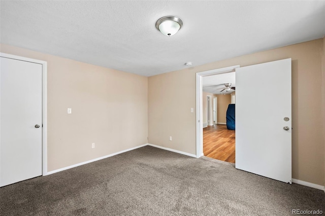carpeted spare room featuring baseboards and ceiling fan
