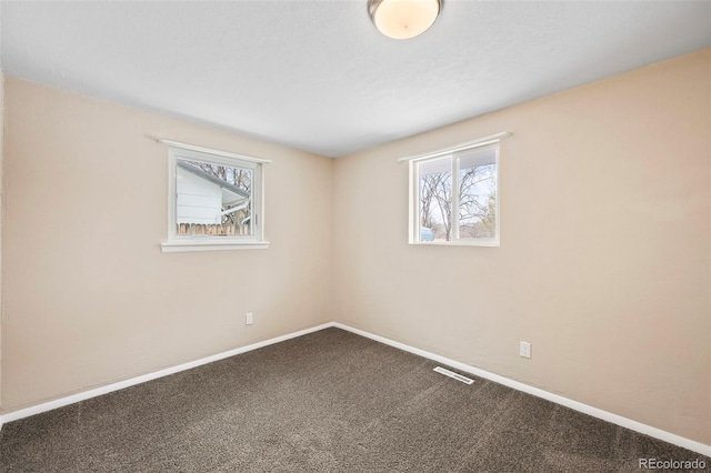 spare room featuring carpet flooring, baseboards, visible vents, and plenty of natural light