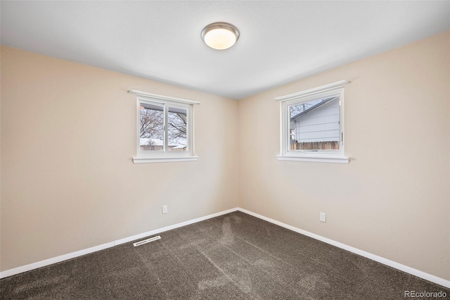 spare room with carpet flooring, baseboards, visible vents, and a healthy amount of sunlight