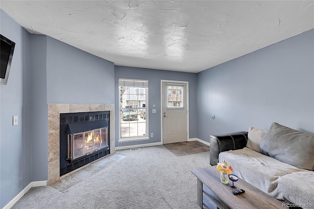 carpeted living area featuring baseboards and a fireplace