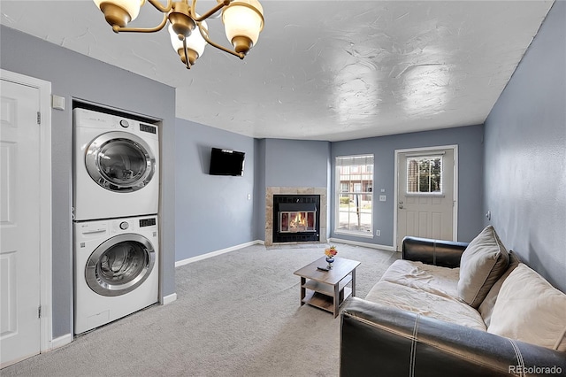 washroom with laundry area, stacked washer / dryer, baseboards, a chandelier, and carpet flooring