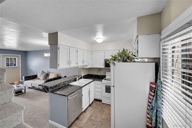 kitchen featuring a textured ceiling, appliances with stainless steel finishes, a sink, white cabinets, and open floor plan