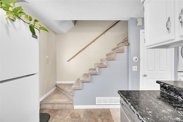 stairway with a textured ceiling, baseboards, and visible vents