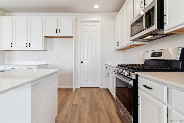 kitchen with light countertops, appliances with stainless steel finishes, light wood-style floors, and white cabinets