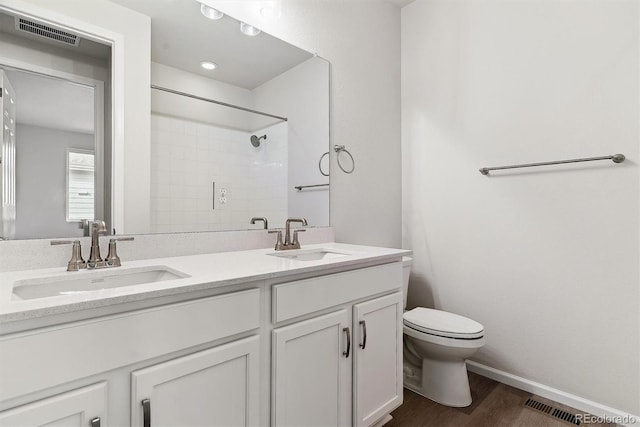 bathroom with vanity, toilet, wood-type flooring, and tiled shower