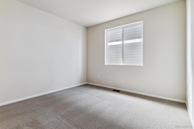 carpeted spare room featuring visible vents and baseboards