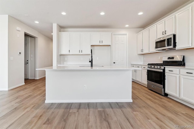 kitchen featuring appliances with stainless steel finishes, an island with sink, recessed lighting, and light wood-style floors