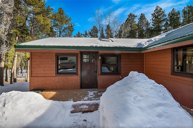 snow covered property entrance featuring a wooden deck