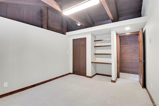 unfurnished bedroom with beamed ceiling and light colored carpet