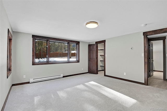 unfurnished bedroom featuring a walk in closet, a baseboard radiator, and a closet