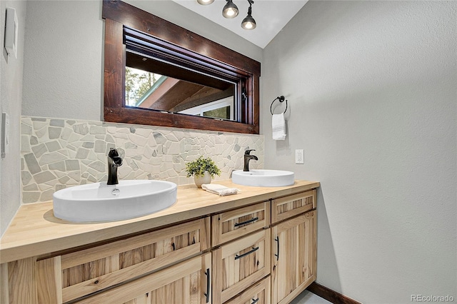 bathroom with backsplash, vanity, and vaulted ceiling