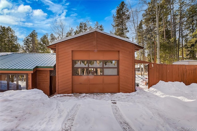 view of snow covered exterior featuring a garage and an outdoor structure