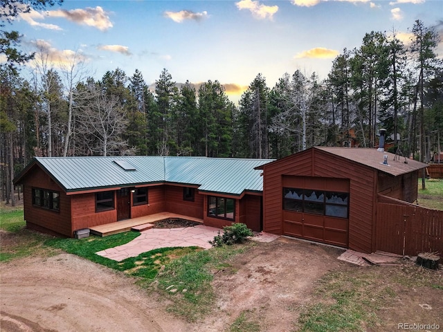 9123 Booker Ln, Conifer, CO 80433 - view of front facade with an attached garage, dirt driveway, a wooded view, and metal roof