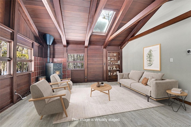 9123 Booker Ln, Conifer, CO 80433 - living area featuring wood ceiling, a wood stove, a skylight, light wood-style flooring, and wooden walls