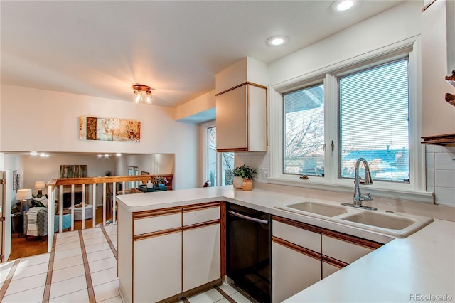 kitchen with light tile patterned flooring, dishwasher, sink, white cabinets, and kitchen peninsula