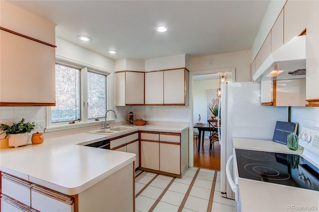 kitchen featuring tasteful backsplash, white range with electric cooktop, kitchen peninsula, and sink