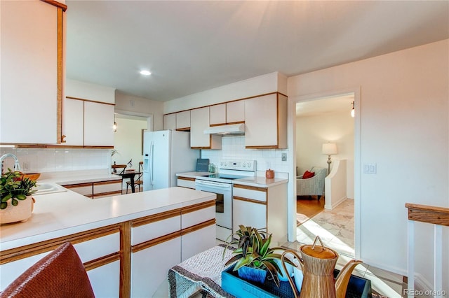 kitchen with sink, tasteful backsplash, kitchen peninsula, white appliances, and white cabinets