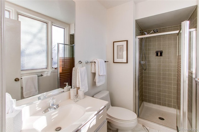 bathroom featuring a shower with door, vanity, and toilet