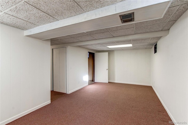 basement featuring a drop ceiling and dark colored carpet