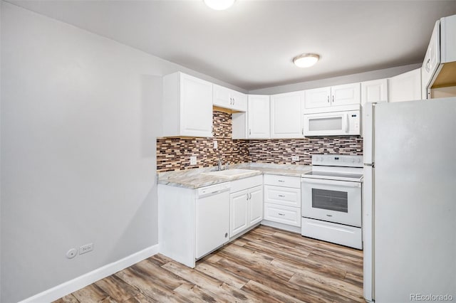 kitchen with white appliances, light hardwood / wood-style flooring, backsplash, white cabinets, and sink