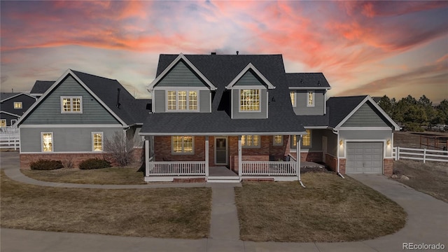 view of front of home with a porch, a garage, brick siding, concrete driveway, and a front lawn