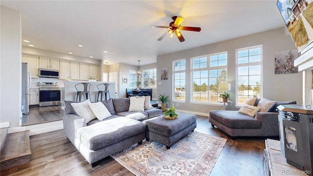 living area with recessed lighting, wood finished floors, a ceiling fan, and baseboards