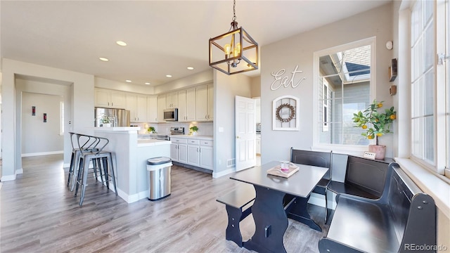 kitchen featuring a kitchen island, a breakfast bar area, stainless steel appliances, light countertops, and pendant lighting