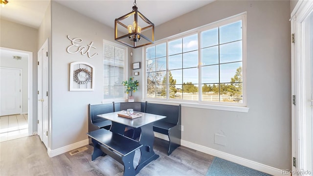 dining area featuring an inviting chandelier, visible vents, baseboards, and wood finished floors