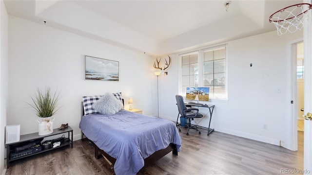 bedroom with a tray ceiling, multiple windows, and wood finished floors