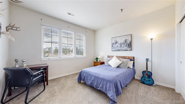 bedroom with baseboards, visible vents, and light colored carpet