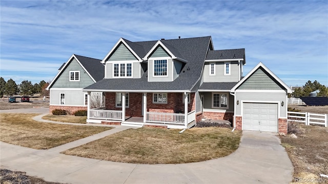 view of front of home featuring brick siding, a porch, concrete driveway, a front yard, and fence