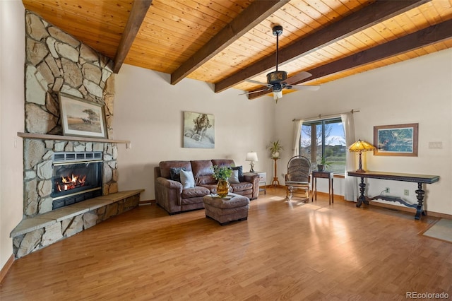 living room with ceiling fan, wooden ceiling, beamed ceiling, hardwood / wood-style floors, and a stone fireplace